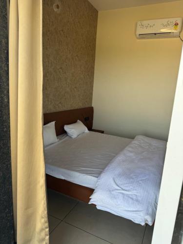 a small bedroom with a bed with white sheets at Infinity Resort & Restaurant in Gauli Palāsia