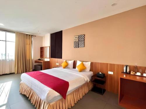 a bedroom with a large bed with a red and white blanket at Garuda Hotel Pontianak in Pontianak