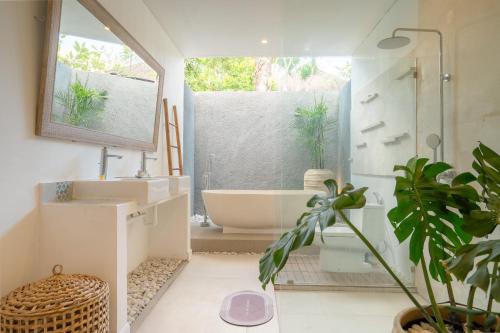a bathroom with a tub and a toilet and a sink at Villa Palma Blanca Canggu by Nagisa Bali in Canggu