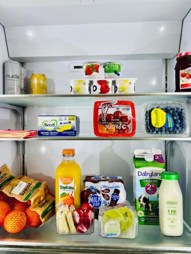 A Gentle Hideaway in the Urban Forest WEST END downtown Vancouver في فانكوفر: ثلاجة مفتوحة مليئة بالأطعمة والمشروبات