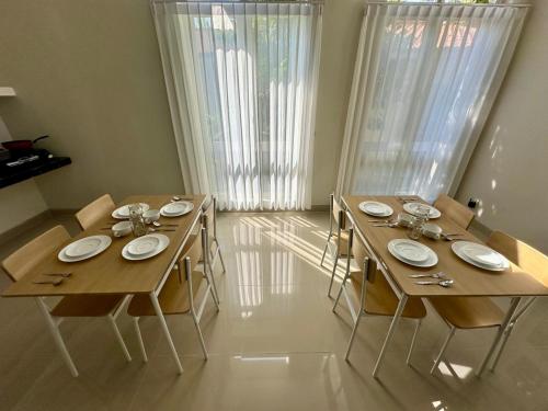 a dining room with two wooden tables and chairs at The Pudina Stay Probolinggo 