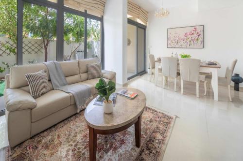 una sala de estar con un sofá y una mesa en Frank Porter - Avencia, Damac Hills 2, en ‘Ūd al Bayḑāʼ