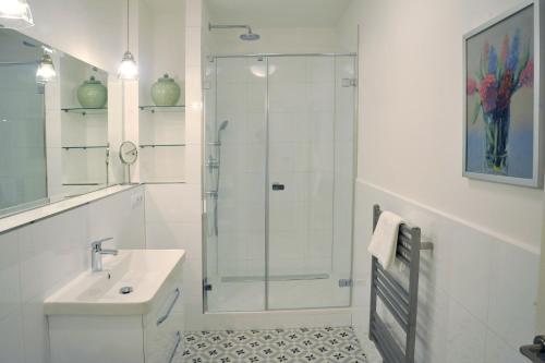 a white bathroom with a shower and a sink at Galerie Suites in Mariánské Lázně