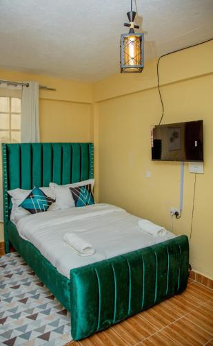 a bed with a green headboard in a room at Verdant Cozy Studio with WI-FI in Nanyuki