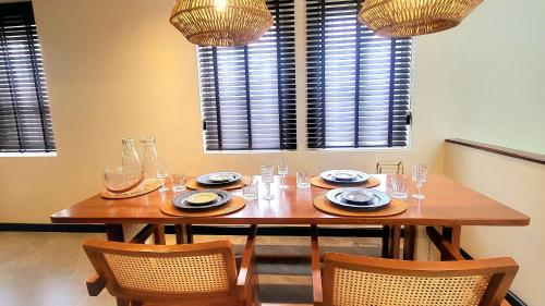 a wooden table with chairs and plates and glasses at Soho House Old Town Bangkok in Bangkok