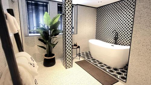a bathroom with a tub and a potted plant at Soho House Old Town Bangkok in Bangkok