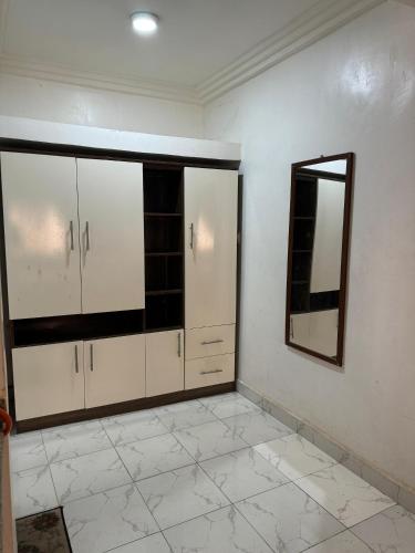 a room with white cabinets and a mirror on the wall at Studio Rooms Gudu in Abuja