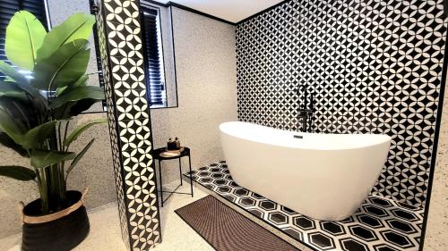 a bathroom with a bath tub and a potted plant at Soho House Old Town Bangkok in Bangkok