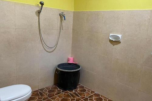 a bathroom with a shower with a toilet and a trash can at Hotel Malinda Pangandaran in Pangandaran