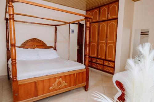 a bedroom with a wooden canopy bed with white sheets at Great Hornbill Holiday Home in Thika