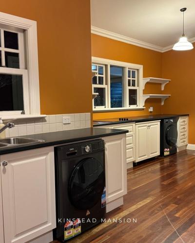 a kitchen with white cabinets and a black dishwasher at Kinstead Mansion - Your exclusive modern country escape in Warragul