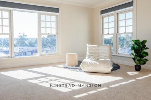 a living room with a white chair and windows at Kinstead Mansion - Your exclusive modern country escape in Warragul