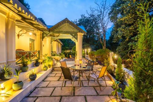a patio with a table and chairs and a pergola at StayVista at The Emily Chalet 7 BR House in Nainital with Bonfire, BBQ in Nainital