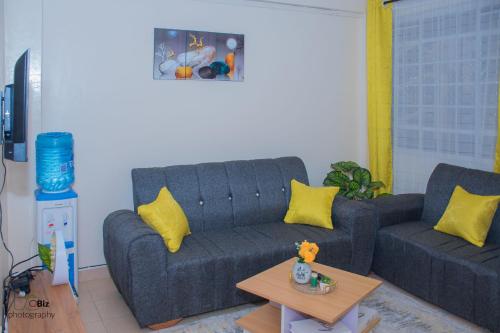 a living room with a blue couch and yellow pillows at Ferrum Apartments in Eldoret