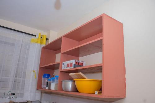 a red shelf in a kitchen with a yellow bowl at Ferrum Apartments in Eldoret