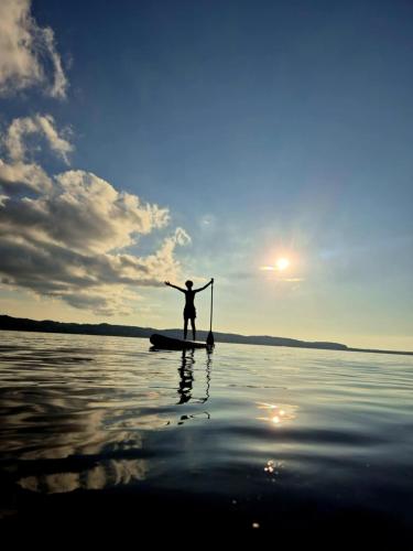 a person is standing on a paddle board on the water at Domek Lubkowo z widokiem in Lubkowo