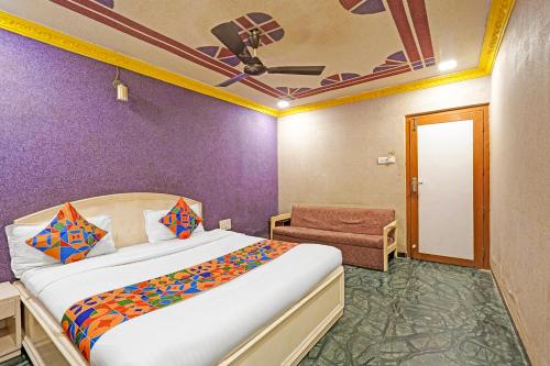 Un dormitorio con una cama y una pared morada. en FabHotel Bridge, en Ahmedabad