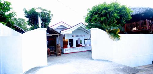 einen weißen Zaun mit einer Palme vor einem Haus in der Unterkunft Nisho House Hiriketiya in Dikwella