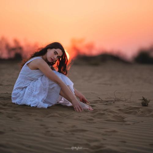a woman sitting on the beach at sunset at Hotel Robin Jaisalmer Near fort view in Jaisalmer