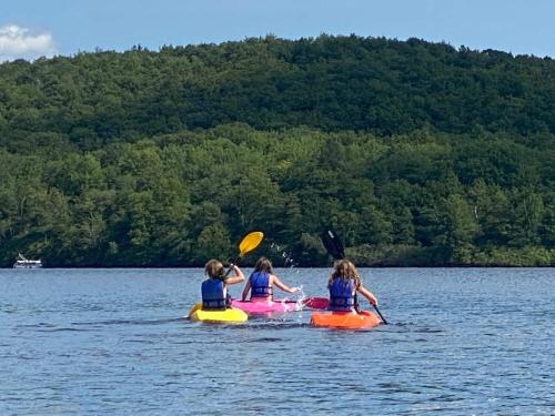 a group of three girls are riding on kayaks on a lake at Pocono Retreat -1 Mile To Lake And Skiing! in Lake Harmony