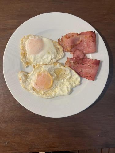 a white plate with eggs and bacon on a table at Palazzo Duca in Chania Town