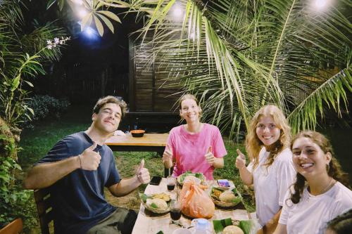 a group of people sitting around a table with food at Sriwedari House Keramas in Gianyar