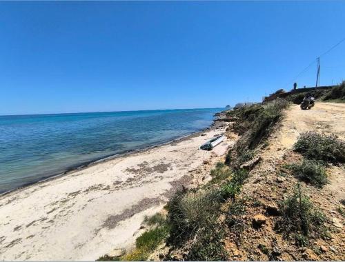 a sandy beach next to the ocean on a sunny day at Villa Sounine Rafraf in Bizerte