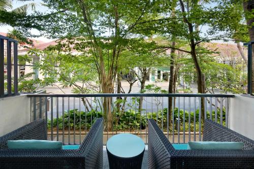 a balcony with two chairs and a table and a fence at Mercure Bali Legian in Legian