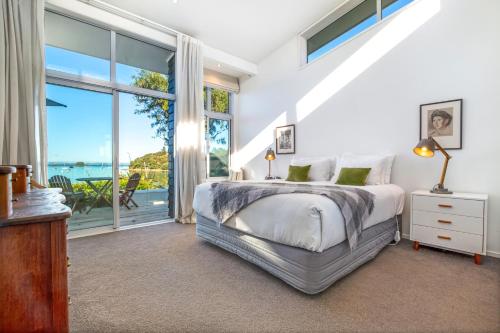a bedroom with a bed and a large window at Shelley Beach Homestead in Waiheke Island
