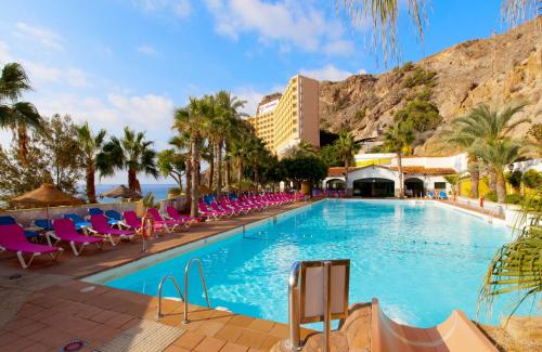 a swimming pool with chairs and a mountain in the background at Diver Aguadulce in Aguadulce