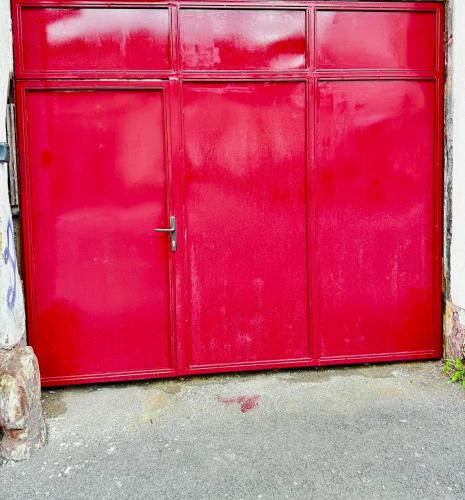 a red metal garage door on a building at Ming with free parking in Braşov