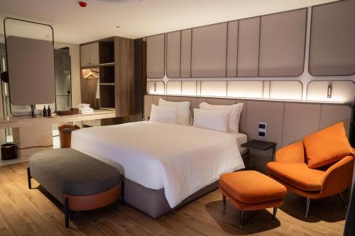a bedroom with a large white bed and two chairs at Richmann Resort Hotel Hatyai in Hat Yai