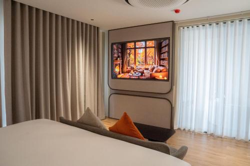 a bedroom with a bed and a tv on a wall at Richmann Resort Hotel Hatyai in Hat Yai