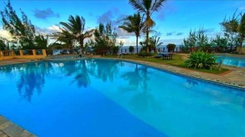a large blue swimming pool with palm trees in the background at Shanzu Oceanfront Apartments and Suites in Mombasa