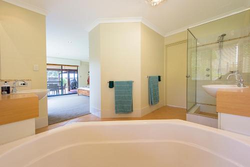 La grande salle de bains est pourvue d'une grande baignoire et d'un lavabo. dans l'établissement Sky Blue Retreat Serene Family Getaway, à North Boyanup