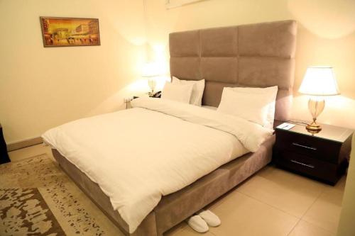 a bedroom with a large bed and a night stand with a lamp at Four Season Guest House in Islamabad