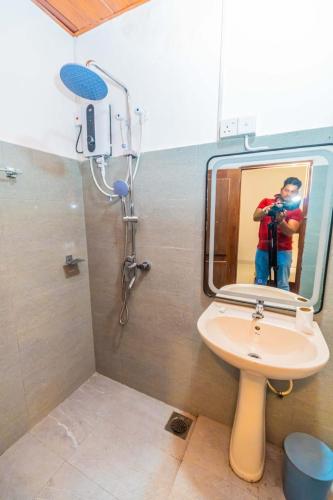 a man taking a picture of a mirror in a bathroom at Wood Land Airport residences in Seeduwa