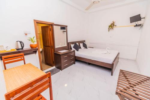 a bedroom with a bed and a desk and a mirror at Wood Land Airport residences in Seeduwa