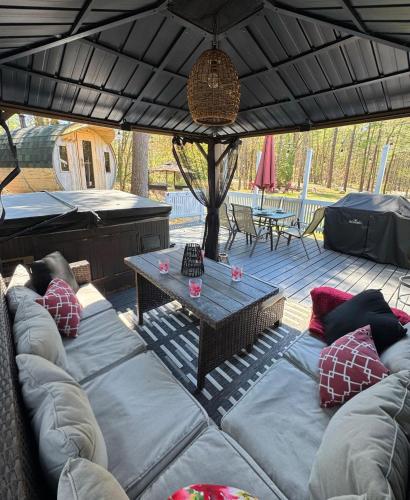 a covered patio with couches and a table at Stunning 3br Waterfront Lake Cottage Hottub&sauna in Gravenhurst