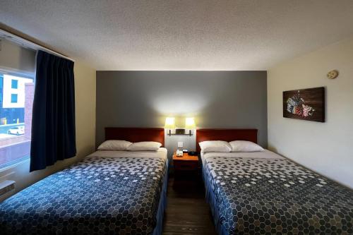 a hotel room with two beds and a window at Econo Lodge Motel Village in Calgary