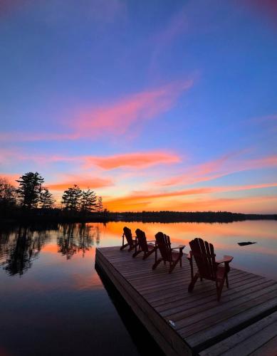 three chairs sitting on a dock in front of a lake at Stunning 3br Waterfront Lake Cottage Hottub&sauna in Gravenhurst