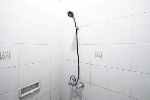 a shower in a bathroom with white tiles at Sartika Hotel in Bandung