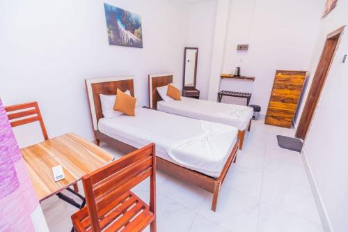 a room with two beds and a table and a desk at Wood Land Airport residences in Seeduwa