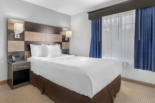 a large bed in a hotel room with a large window at MainStay Suites Madison Airport in Madison