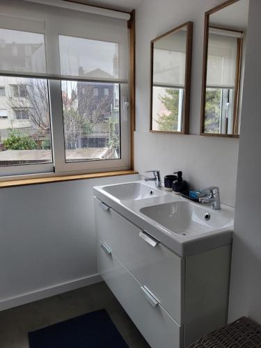 a white bathroom with two sinks and two windows at Casa da travessa familial e com terraço in Porto