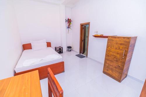 a small bedroom with a bed and a wooden cabinet at Wood Land Airport residences in Seeduwa