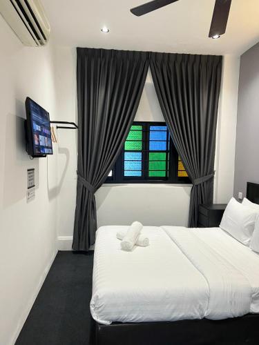 a bedroom with a white bed and a window at Quee Hotel in George Town