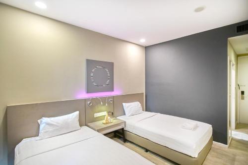 two beds in a room with purple lighting at Empire Damansara Petaling Jaya by COBNB in Petaling Jaya