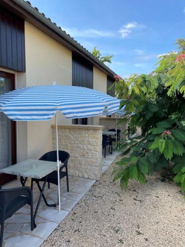 a patio with a blue umbrella and chairs and tables at Hôtel Le Mas del Pechs - Chambres avec terrasse in Sarlat-la-Canéda