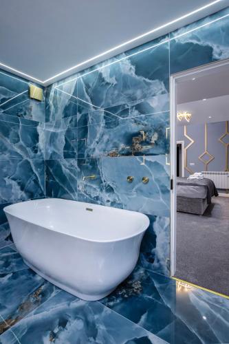 a bathroom with a white tub and a blue marble wall at Swish Luxury Holiday Apartments 2 in Blackpool